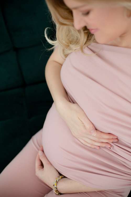 Person In All Pink Smiles And Holds Her Belly Photo
