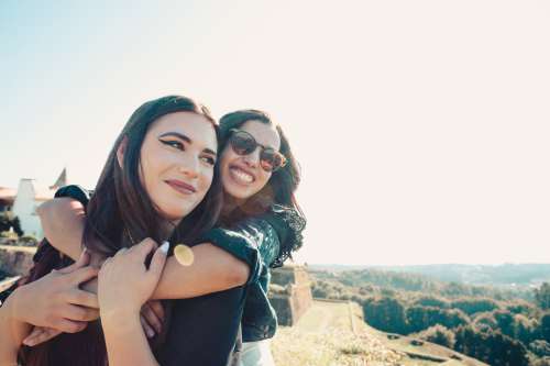 Woman Hugs Other Woman From Behind Photo
