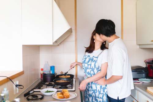 Two People Share A Kiss In The Kitchen Cooking Photo