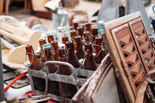 Old vintage brown glass bottles in a rusty metal crate at a flea market