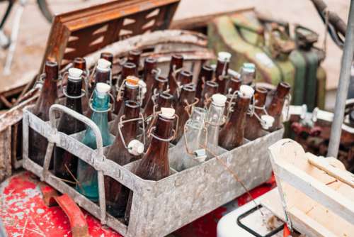 Old vintage brown glass bottles in a rusty metal crate at a flea market 2