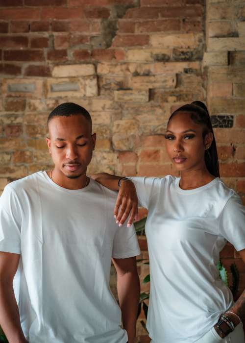 Two People Stands Together In Front Of A Red Brick Wall Photo