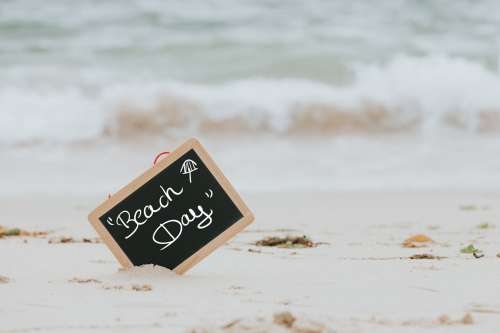 Blackboard That Reads Beach Day Sticks Out Of A Sandy Beach Photo