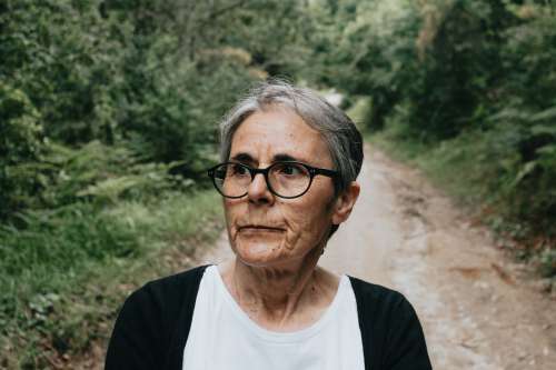 Woman In Glasses Looks Left On A Green Lined Dirt Trail Photo