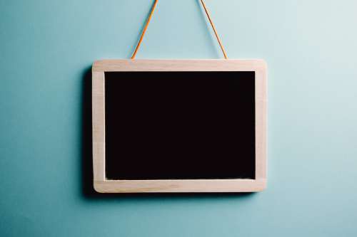 Blank Wood Frame Chalkboard Hangs On A Blue Wall Photo