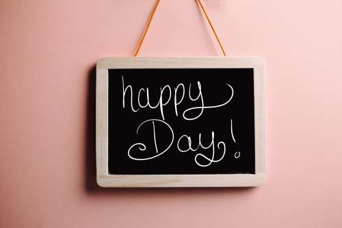 Blackboard Reads Happy Day Against Orange Background Photo