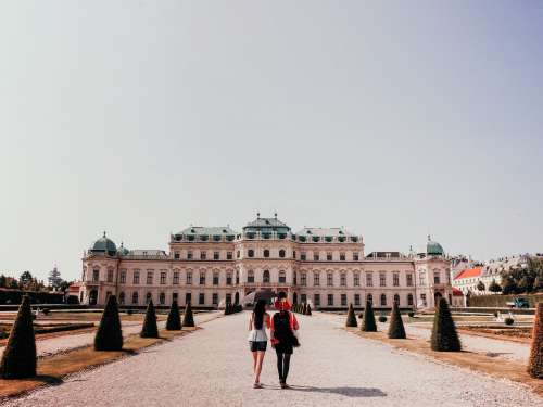 Two People Walk Towards A Large White Building Photo