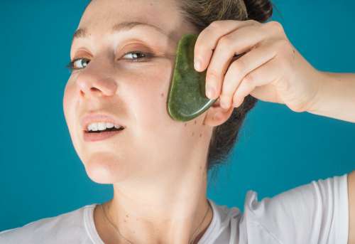 Woman Holds A Jade Face Massager To Her Face Photo