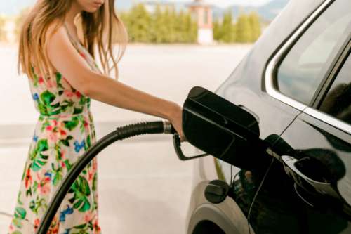 Young Woman Refueling Car at Gas Station on a Sunny Day
